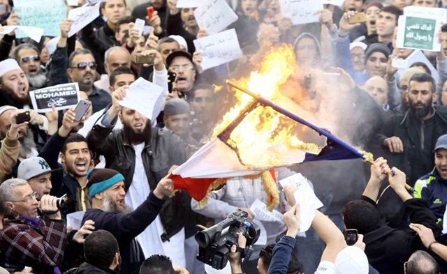 Demonstrators burn the French national flag after Friday prayers in Algiers