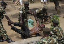 Les forces de l'ordre soulèvent un blessé présumé membre des milices IBONERAKURE attaqué par les manifestants