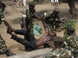 Les forces de l'ordre soulèvent un blessé présumé membre des milices IBONERAKURE attaqué par les manifestants