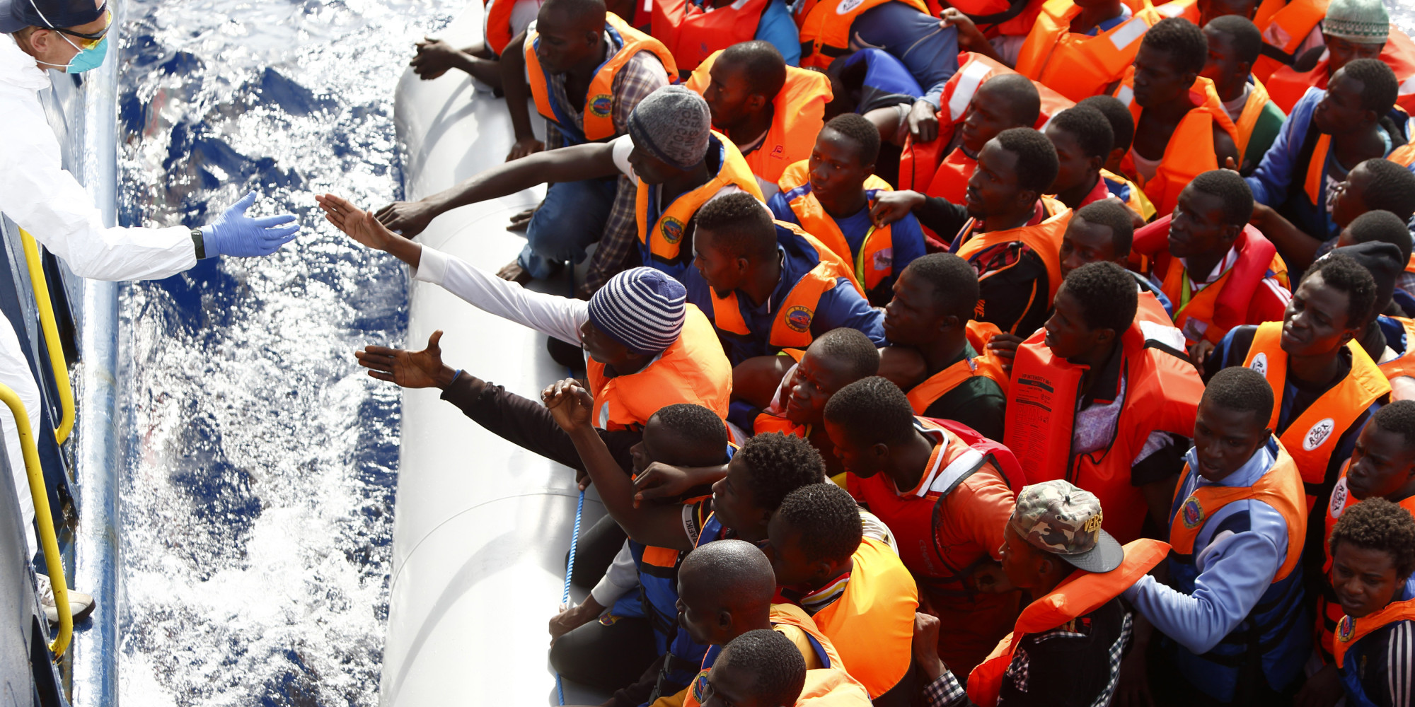 Handout photo shows a group of 104 sub-Saharan Africans on board a rubber dinghy preparing to board the NGO Migrant Offshore Aid Station ship Phoenix some 25 miles off the Libyan coast